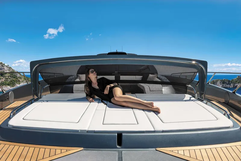  Yacht Photos Pics 2025 Riva Folgore yacht with woman lounging on deck under clear blue sky.