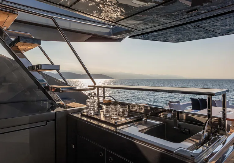  Yacht Photos Pics Luxurious 2025 Riva Folgore yacht deck with modern bar setup, overlooking serene ocean view.