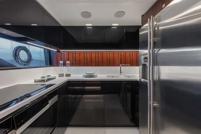  Yacht Photos Pics Modern kitchen interior in 2025 Riva Folgore yacht, featuring sleek black cabinetry and stainless steel appliances.