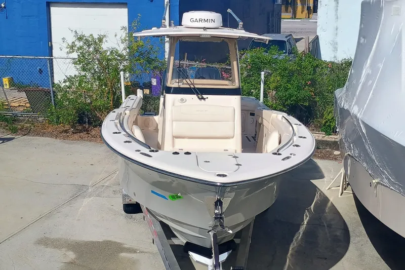 271-508 Brokerage Joe Yacht Photos Pics 2023 Grady-White Canyon 271 boat on trailer, parked outdoors near blue building.