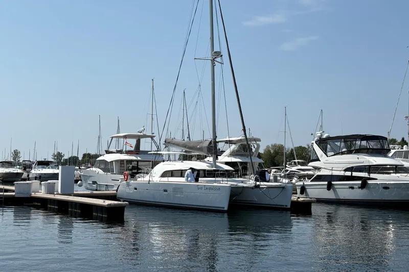 Too Impulsive Yacht Photos Pics 2014 Lagoon 380 S2 catamaran docked in a marina, surrounded by other boats.