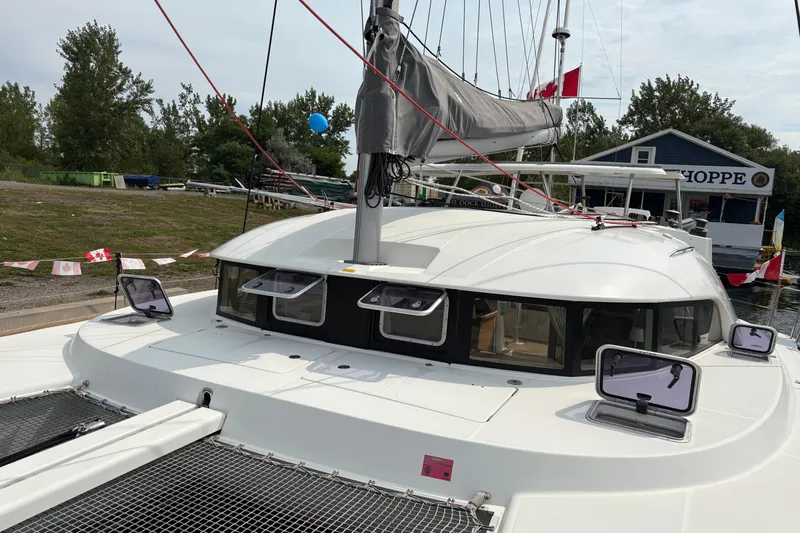 Too Impulsive Yacht Photos Pics 2014 Lagoon 380 S2 catamaran docked near a shop, surrounded by trees and flags.
