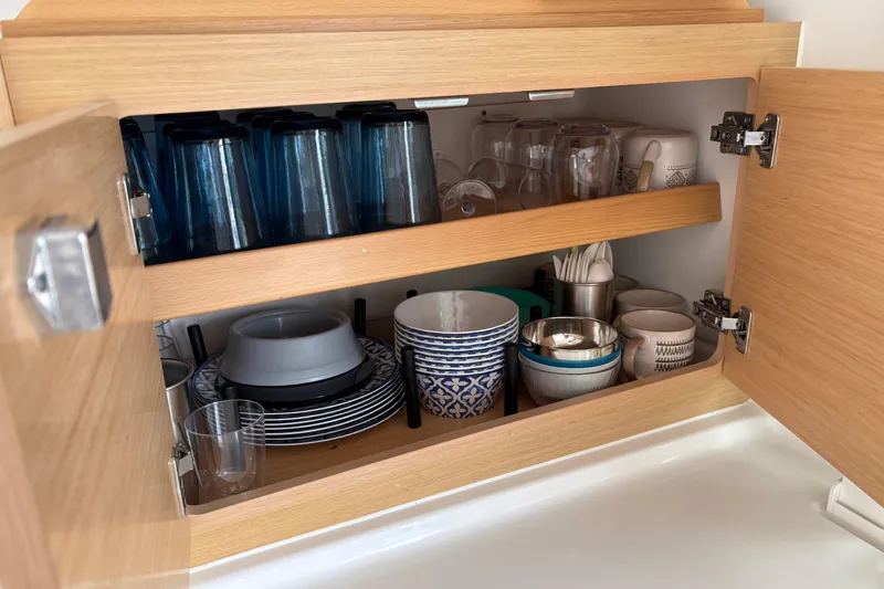 Too Impulsive Yacht Photos Pics Open wooden cabinet with neatly arranged dishes and glasses on a Lagoon 380 S2, 2014.