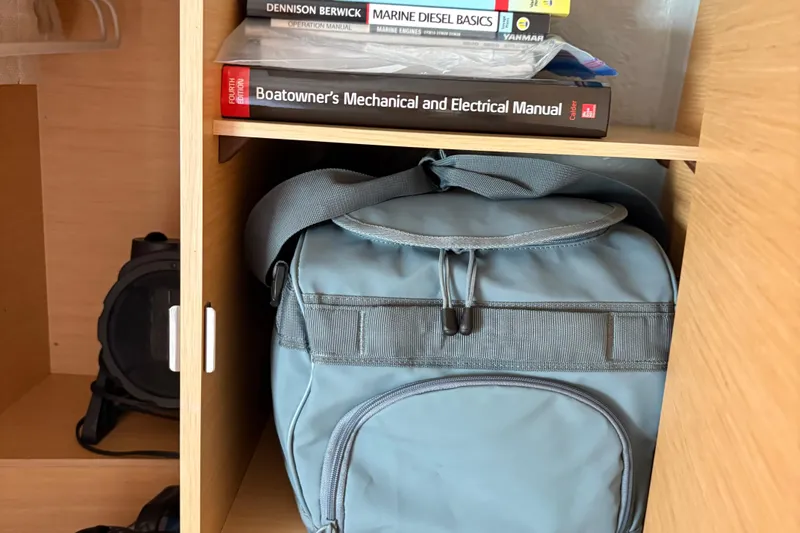 Too Impulsive Yacht Photos Pics Books and a blue bag in a wooden shelf on a Lagoon 380 S2, 2014 model.