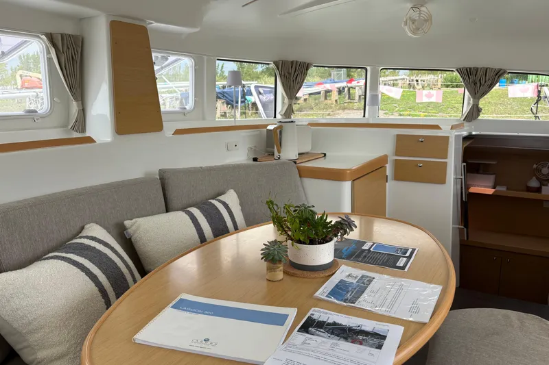 Too Impulsive Yacht Photos Pics Interior of 2014 Lagoon 380 S2 catamaran with dining area and documents on table.