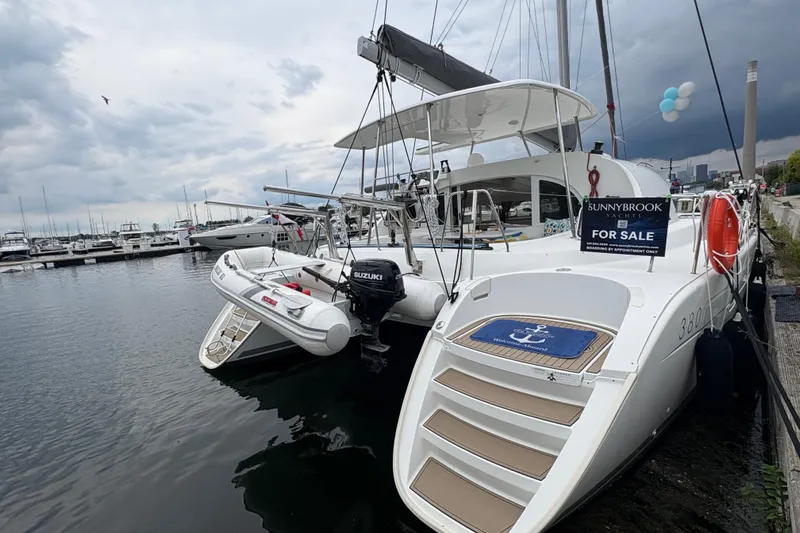 Too Impulsive Yacht Photos Pics 2014 Lagoon 380 S2 catamaran for sale at marina, overcast sky, inflatable boat attached.