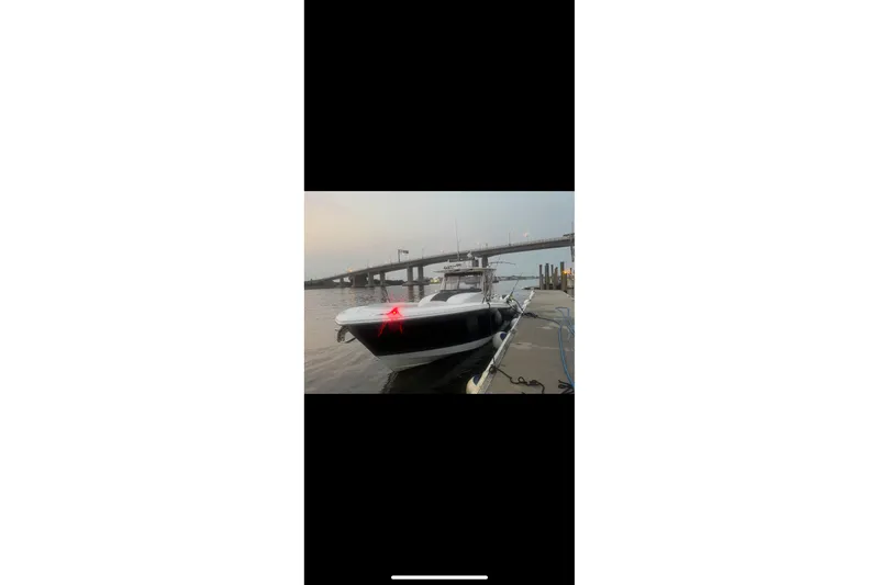  Yacht Photos Pics 2017 Edgewater 368CC boat docked near a bridge at sunset.
