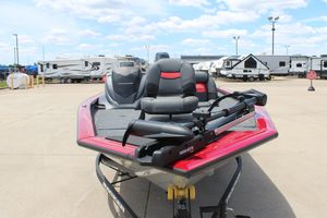 2025 Tracker Pro Team 175 boat, red and black, parked near RVs under a cloudy sky.