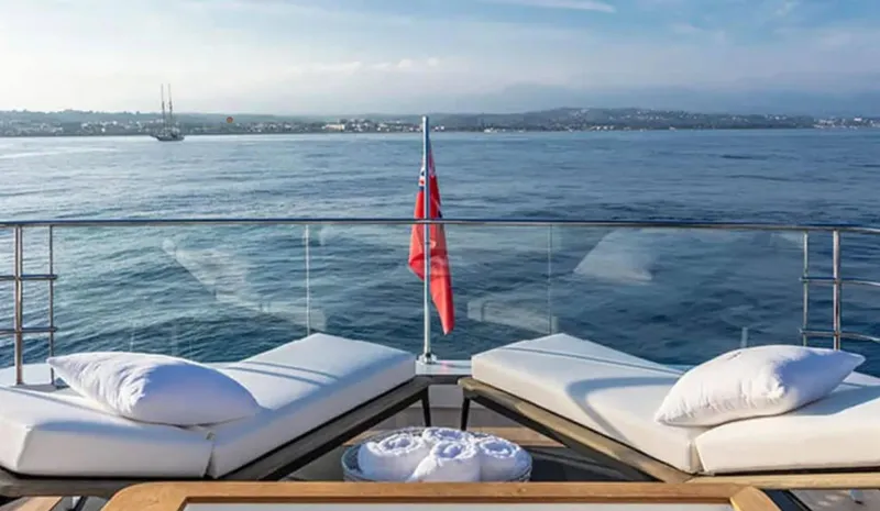  Yacht Photos Pics Luxurious Pearl 95 yacht deck with sun loungers, ocean view, and red flag, 2025 model.