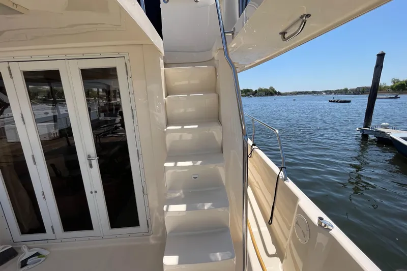  Yacht Photos Pics 2005 Mainship 400 Trawler with stairs, docked by a serene lake under clear skies.