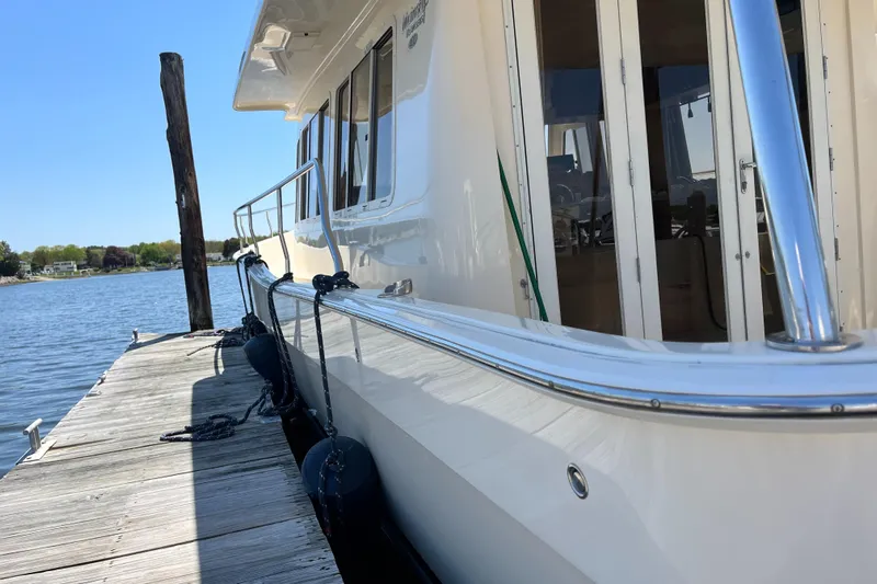 Yacht Photos Pics 2005 Mainship 400 Trawler docked by a serene waterfront.