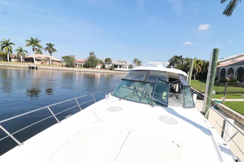 Nauti Buoy Yacht Photos Pics 2007 Cruisers 520 Express yacht docked by waterfront homes and palm trees.