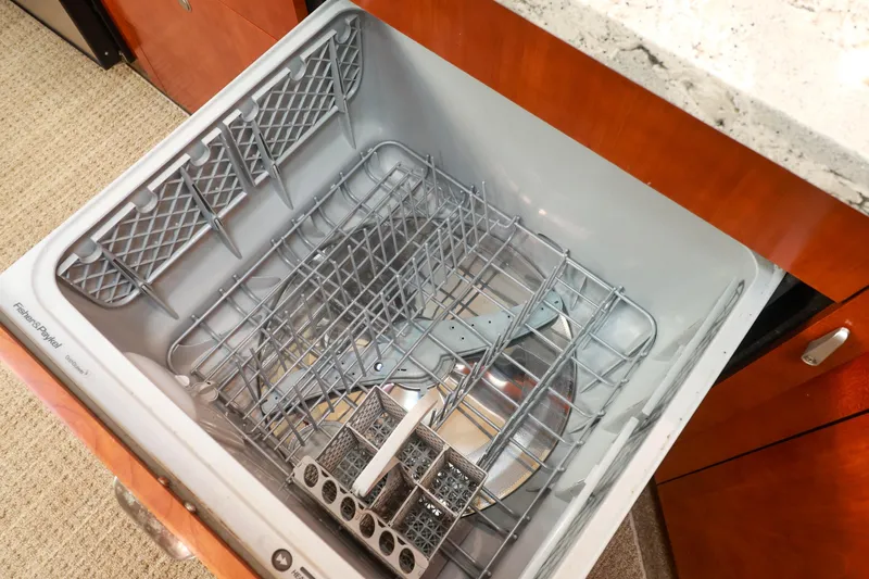 Nauti Buoy Yacht Photos Pics Open dishwasher in 2007 Cruisers 520 Express yacht kitchen, featuring wooden cabinetry and granite countertop.