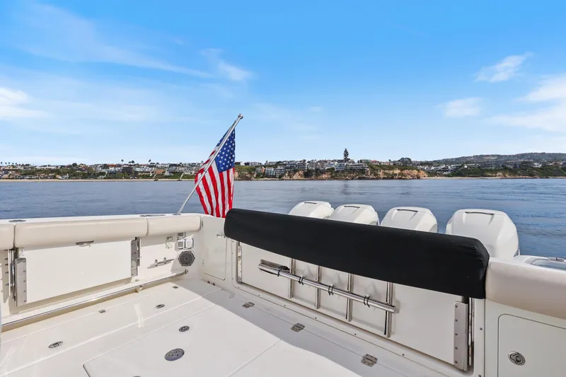 Fan Tail III Yacht Photos Pics 2018 Boston Whaler 420 Outrage boat with American flag, coastal view in background.