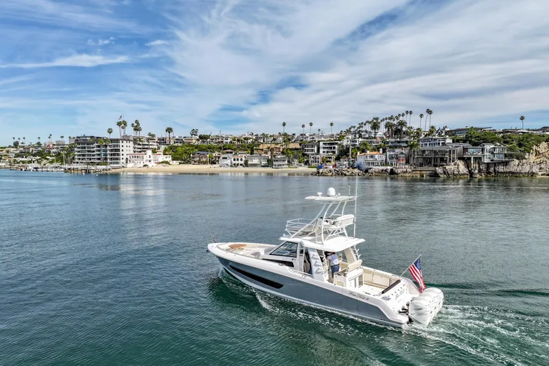Fan Tail III Yacht Photos Pics 2018 Boston Whaler 420 Outrage cruising near coastal homes under a blue sky.