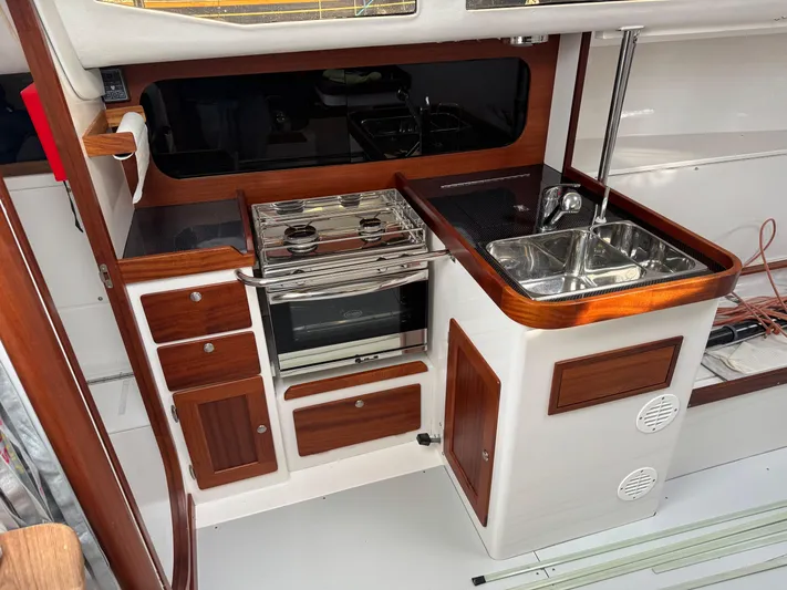 Ace Yacht Photos Pics 2019 J Boats J/121 yacht interior with compact kitchen and wooden cabinetry.