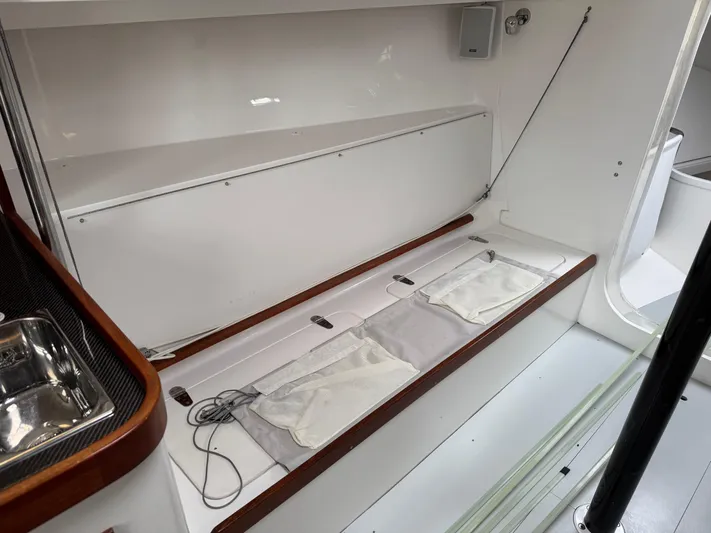 Ace Yacht Photos Pics Interior of 2019 J Boats J/121 sailboat, featuring sleek white seating and storage area.