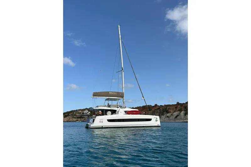 Platinum Yacht Photos Pics 2023 Bali 4.6 catamaran sailing in clear blue waters near rocky coastline.
