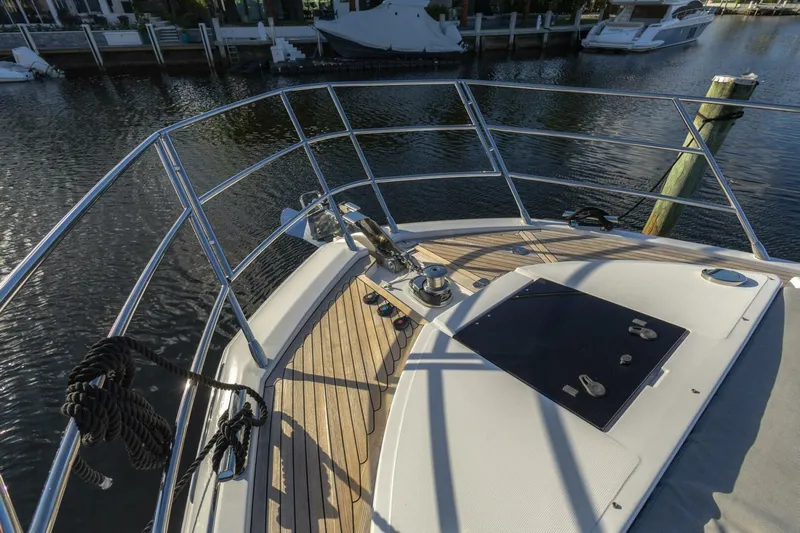 Asymmetry Yacht Photos Pics 2023 Azimut S6 Sport-Fly yacht bow with sleek deck and railing, docked by the water.