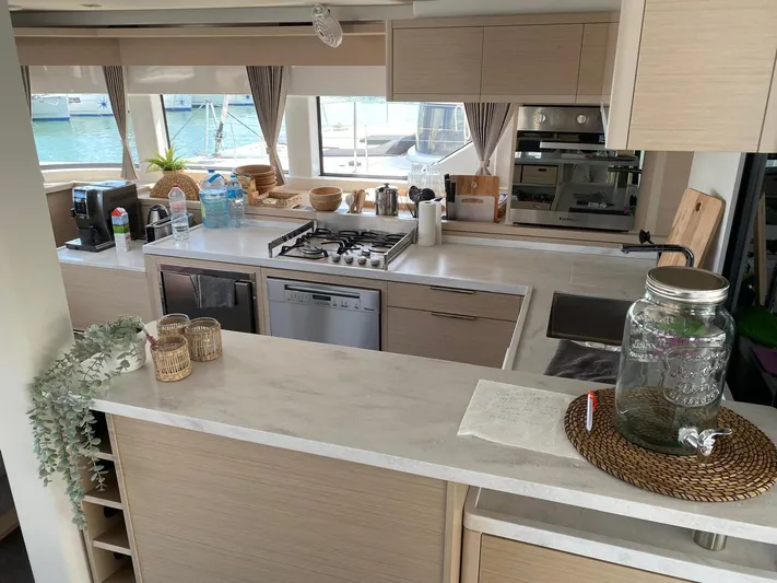 Slow Down Yacht Photos Pics Modern kitchen interior on 2023 Lagoon 55 yacht, featuring sleek countertops and appliances.