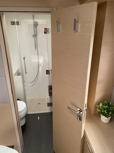 Slow Down Yacht Photos Pics Modern bathroom interior on 2023 Lagoon 55 yacht, featuring shower and toilet.