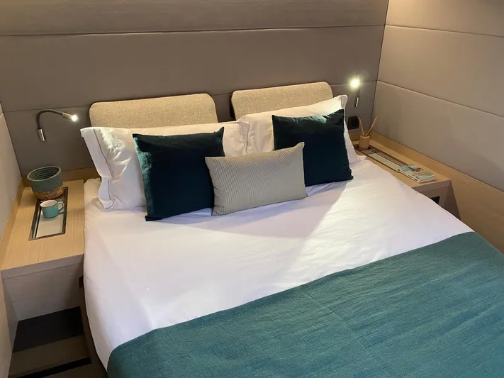 Slow Down Yacht Photos Pics Luxurious bedroom interior of 2023 Lagoon 55 yacht with elegant bedding and modern lighting.