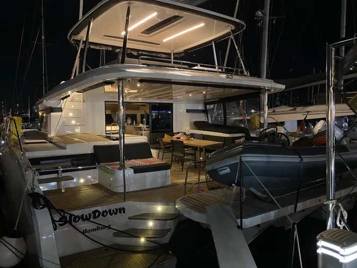 Slow Down Yacht Photos Pics Luxurious 2023 Lagoon 55 yacht at night, featuring elegant outdoor seating and dining area.