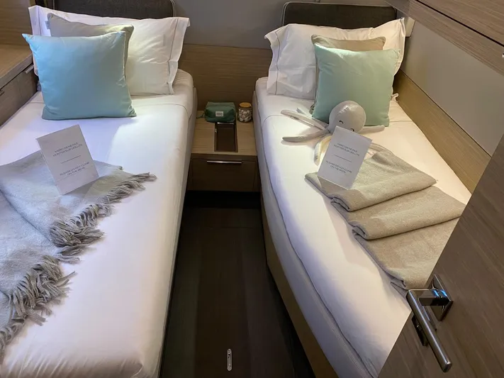 Slow Down Yacht Photos Pics Twin beds in a 2023 Lagoon 55 yacht cabin, with pillows and blankets.