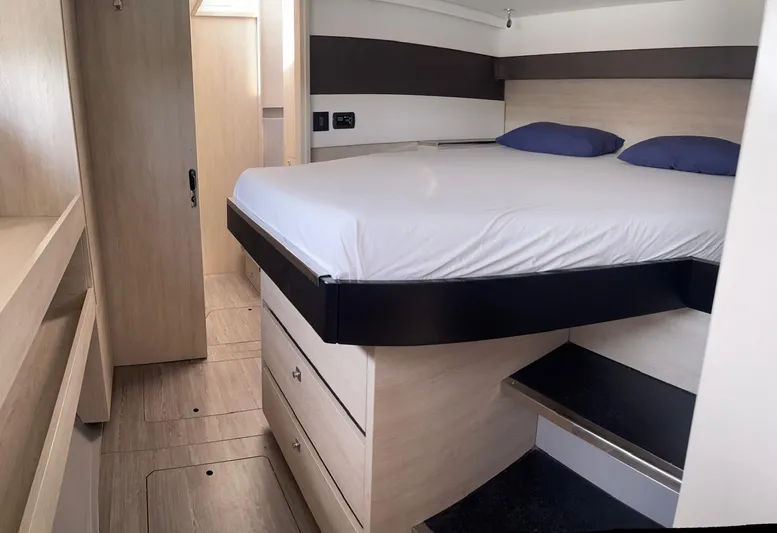 Seventeen Yacht Photos Pics Modern bedroom interior of Leopard 50 yacht, 2020 model, featuring a raised bed and wooden cabinetry.