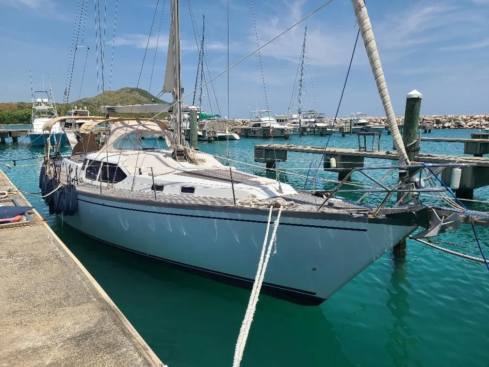 Sailboat Comet 54 DH 2001 docked in a marina with clear blue water.