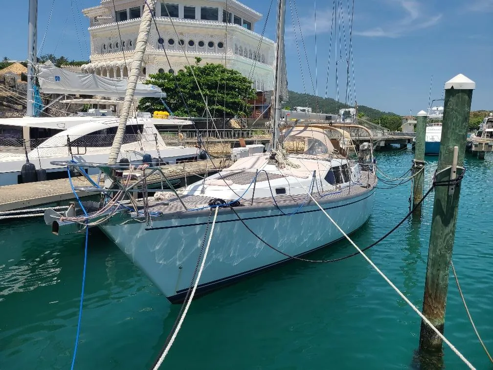 Sailboat Comet 54 DH 2001 docked in a marina with clear blue water.