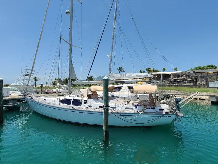 Taita I Yacht Photos Pics Sailboat Comet 54 DH 2001 docked in clear turquoise water under a blue sky.