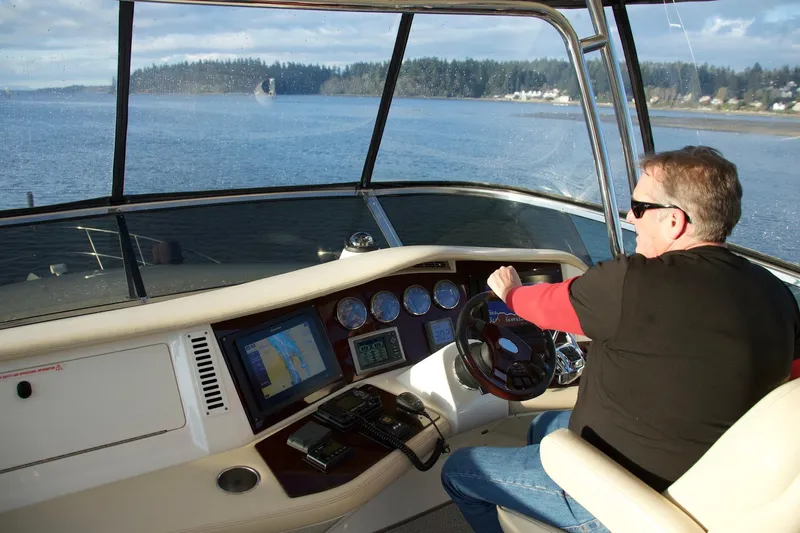  Yacht Photos Pics Man steering 2012 Meridian 541 Sedan yacht on a scenic lake.