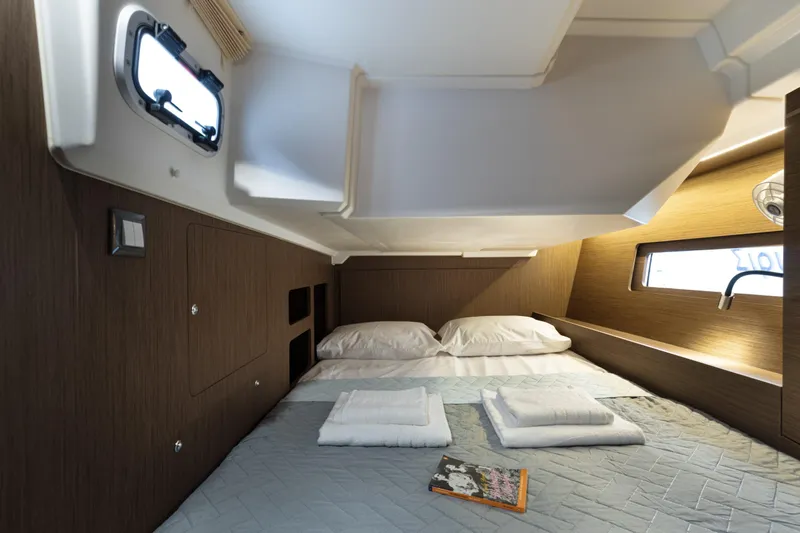  Yacht Photos Pics Cozy cabin interior of 2020 Beneteau Oceanis 46.1 yacht with bed and porthole window.