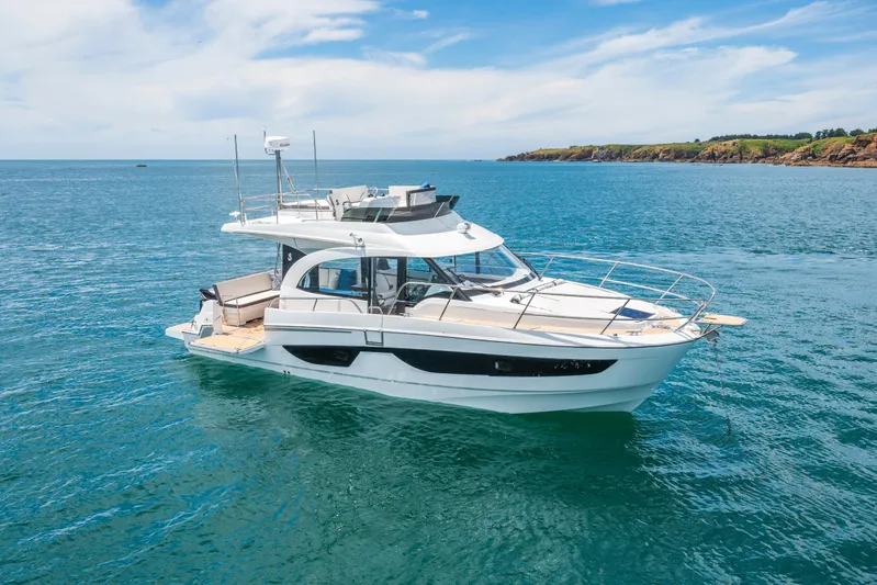  Yacht Photos Pics 2025 Beneteau Antares 11 Fly yacht on serene blue waters, coastal backdrop.