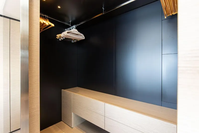 Haiami Yacht Photos Pics Luxurious walk-in closet on Custom Line Navetta 33 yacht, 2022 model, with sleek black walls and wooden hangers.