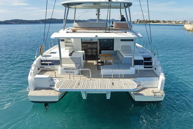 Saliska Yacht Photos Pics 2023 Lagoon 55 catamaran on clear blue water, showcasing spacious deck and modern design.