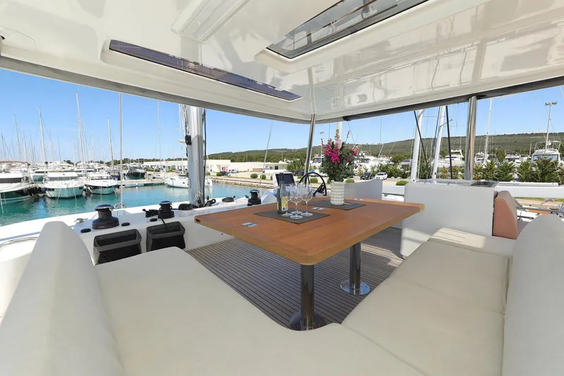 Saliska Yacht Photos Pics Luxurious 2023 Lagoon 55 yacht interior with elegant seating and dining area, docked at marina.