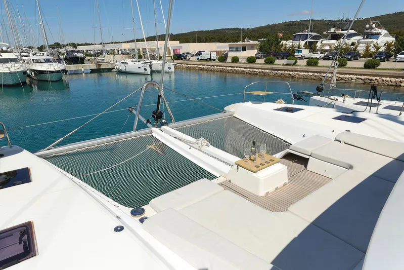 Saliska Yacht Photos Pics 2023 Lagoon 55 catamaran docked in marina, featuring spacious deck and netting.