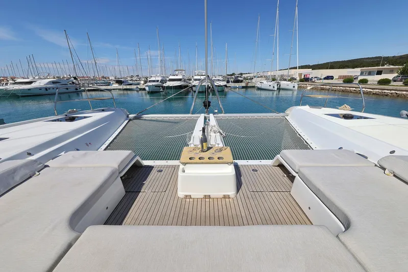 Saliska Yacht Photos Pics 2023 Lagoon 55 catamaran docked in a marina, showcasing spacious deck and seating area.