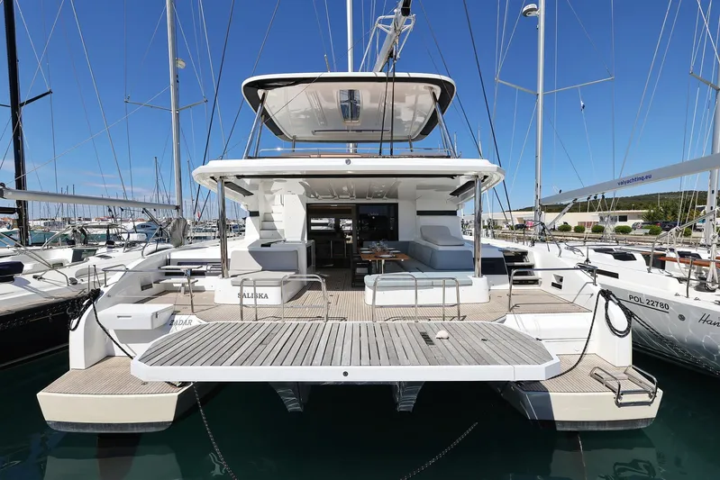 Saliska Yacht Photos Pics 2023 Lagoon 55 yacht, rear view, docked in marina under clear blue sky.