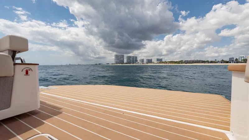  Yacht Photos Pics 2024 Tiara Yachts 48 LE deck overlooking ocean and city skyline under cloudy sky.