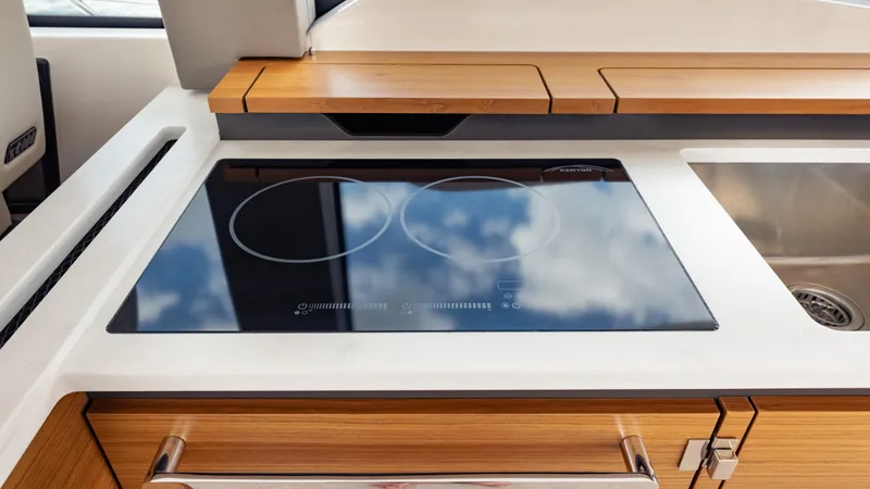  Yacht Photos Pics Modern kitchen area on 2024 Tiara Yachts 48 LE, featuring sleek induction cooktop.