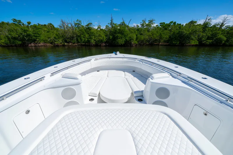  Yacht Photos Pics Luxurious 2026 HCB 48 Campeon boat interior with white seating, surrounded by lush greenery.