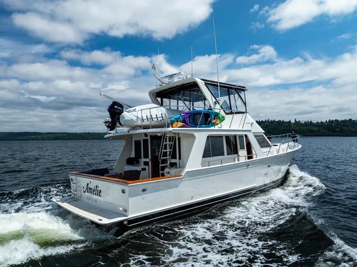 Am&eacute;lie Yacht Photos Pics 1997 Offshore Yachts 52 Sedan cruising on open water under a partly cloudy sky.