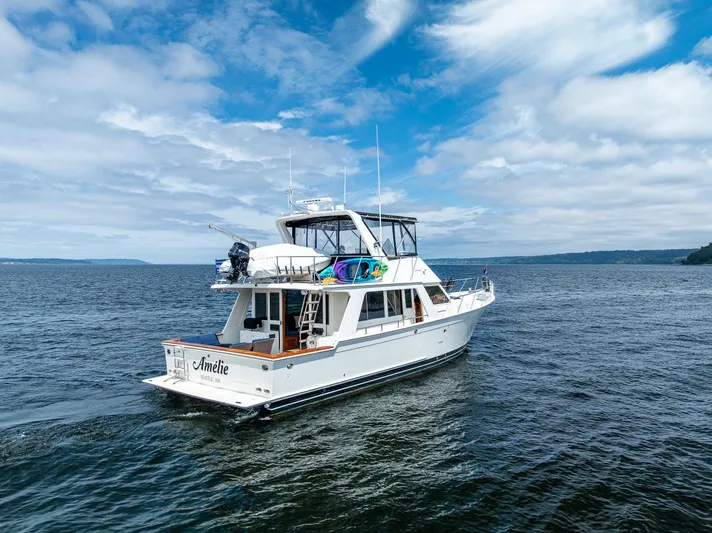 Am&eacute;lie Yacht Photos Pics Offshore Yachts 52 Sedan, 1997 model, cruising on open water under a partly cloudy sky.