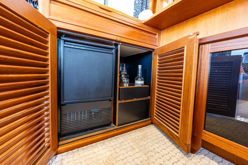 Am&eacute;lie Yacht Photos Pics Wooden cabinet with mini fridge and liquor storage on 1997 Offshore Yachts 52 Sedan.