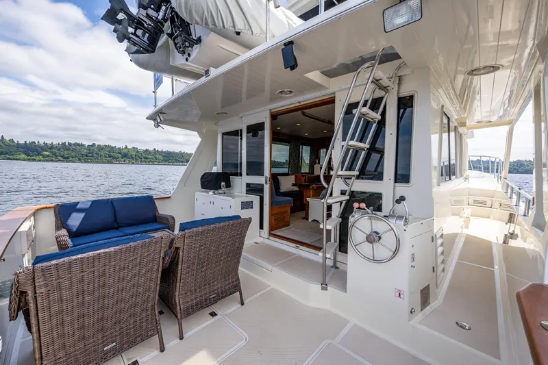 Am&eacute;lie Yacht Photos Pics 1997 Offshore Yachts 52 Sedan with outdoor seating and ladder, docked on a serene waterway.