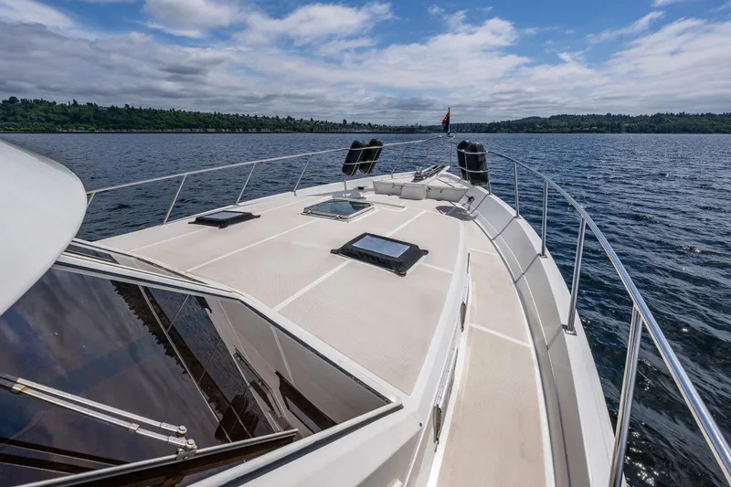 Am&eacute;lie Yacht Photos Pics 1997 Offshore Yachts 52 Sedan cruising on a serene lake under a partly cloudy sky.