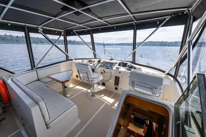 Am&eacute;lie Yacht Photos Pics 1997 Offshore Yachts 52 Sedan helm with panoramic windows and seating, overlooking serene waters.